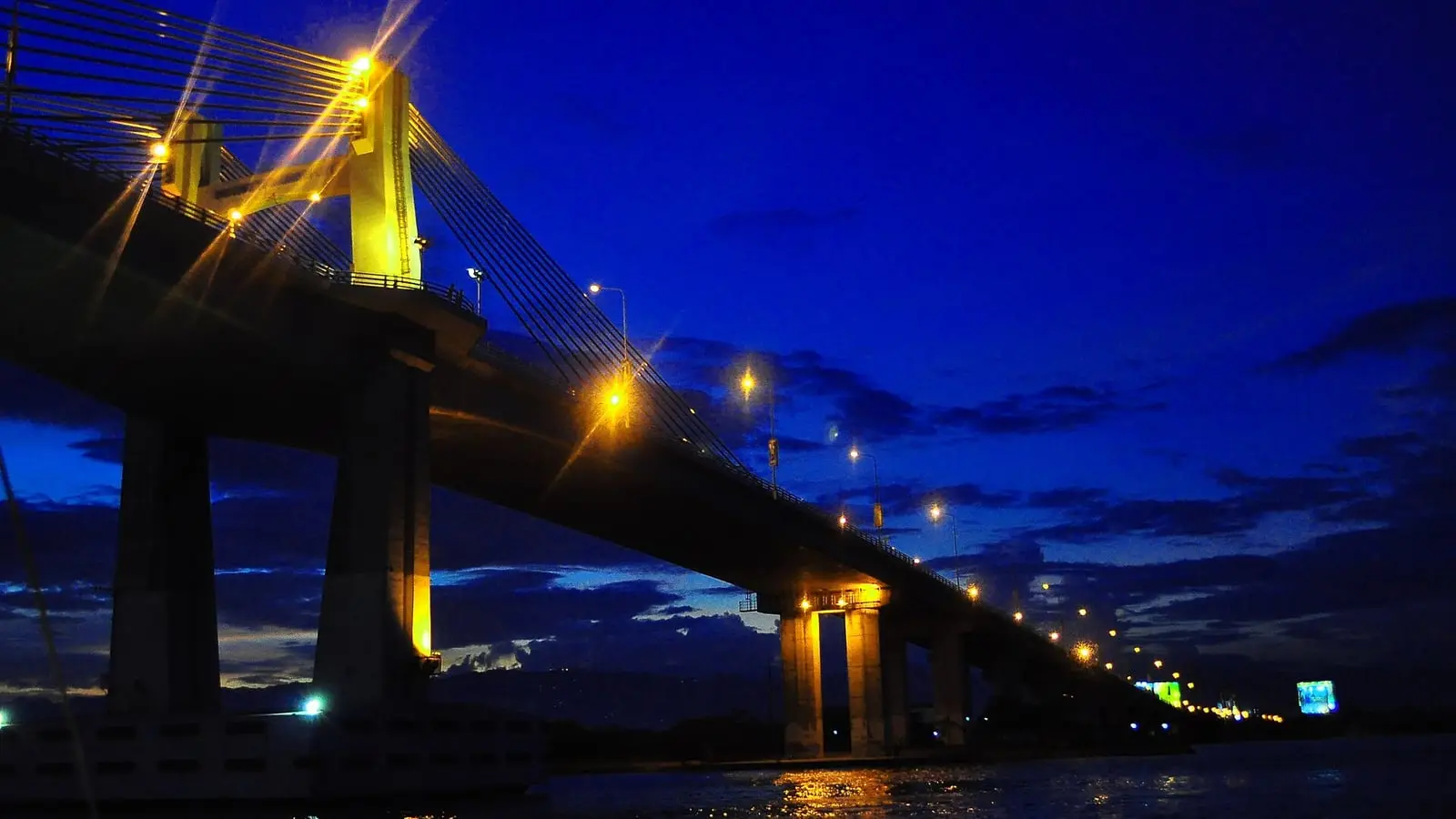 Golden dusk spreading across the tranquil waters of the Mactan Channel framed by traditional outrigger boats