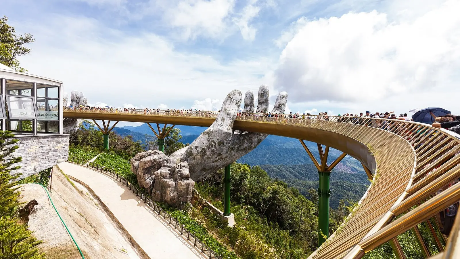 Giant weathered stone hands cradling the gleaming Golden Bridge high above the clouds at Ba Na Hills