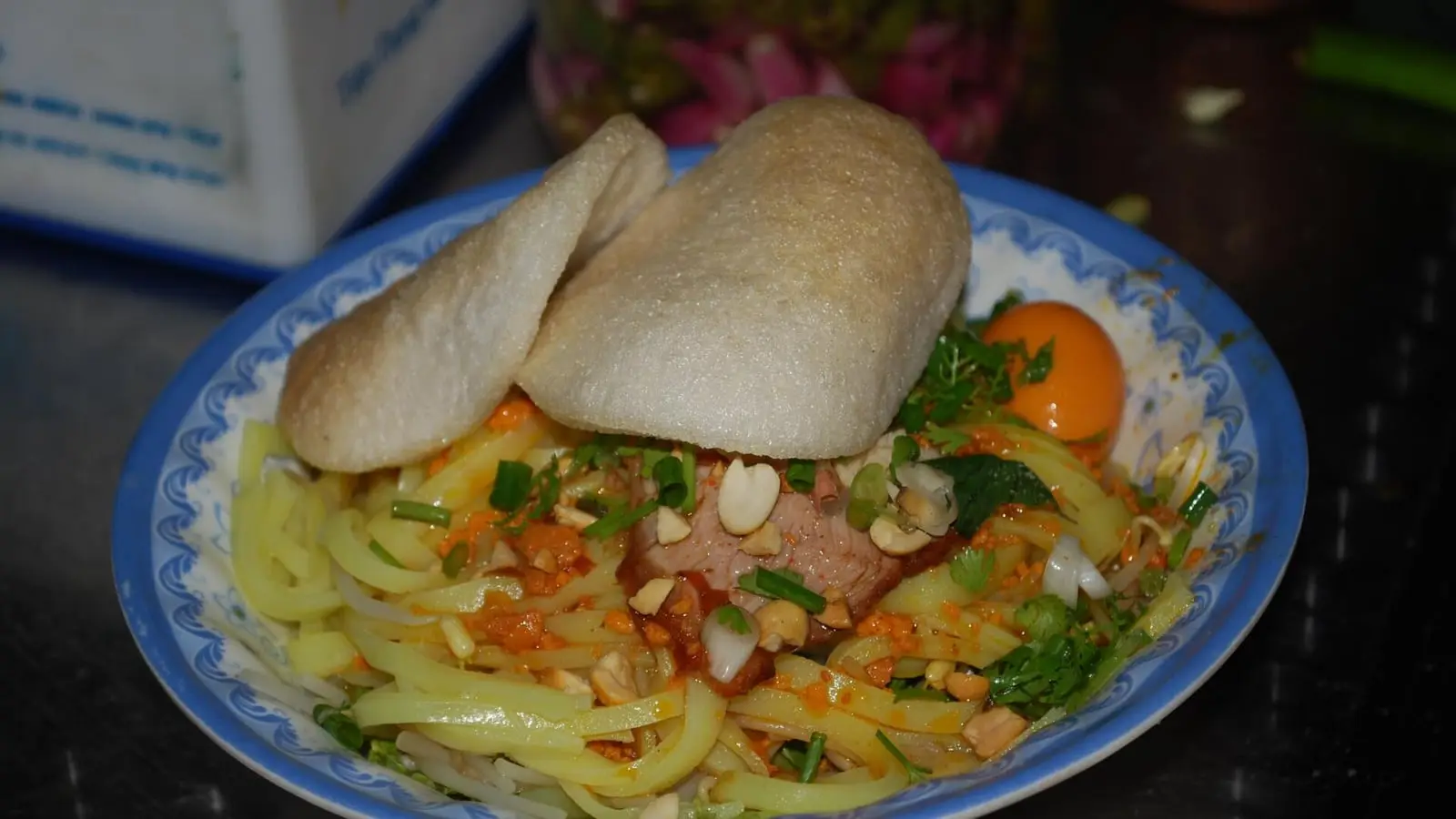 Central Vietnamese Mi Quang turmeric rice noodles topped with shrimp, pork, roasted peanuts, and crispy rice crackers
