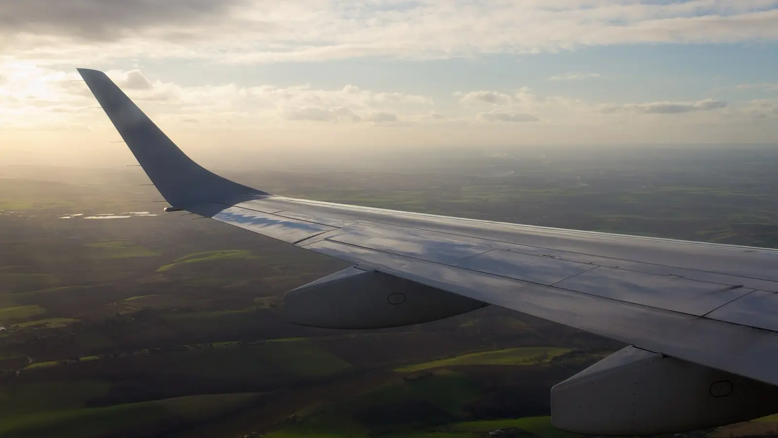 Jet wing climbing into twilight above the airport runway