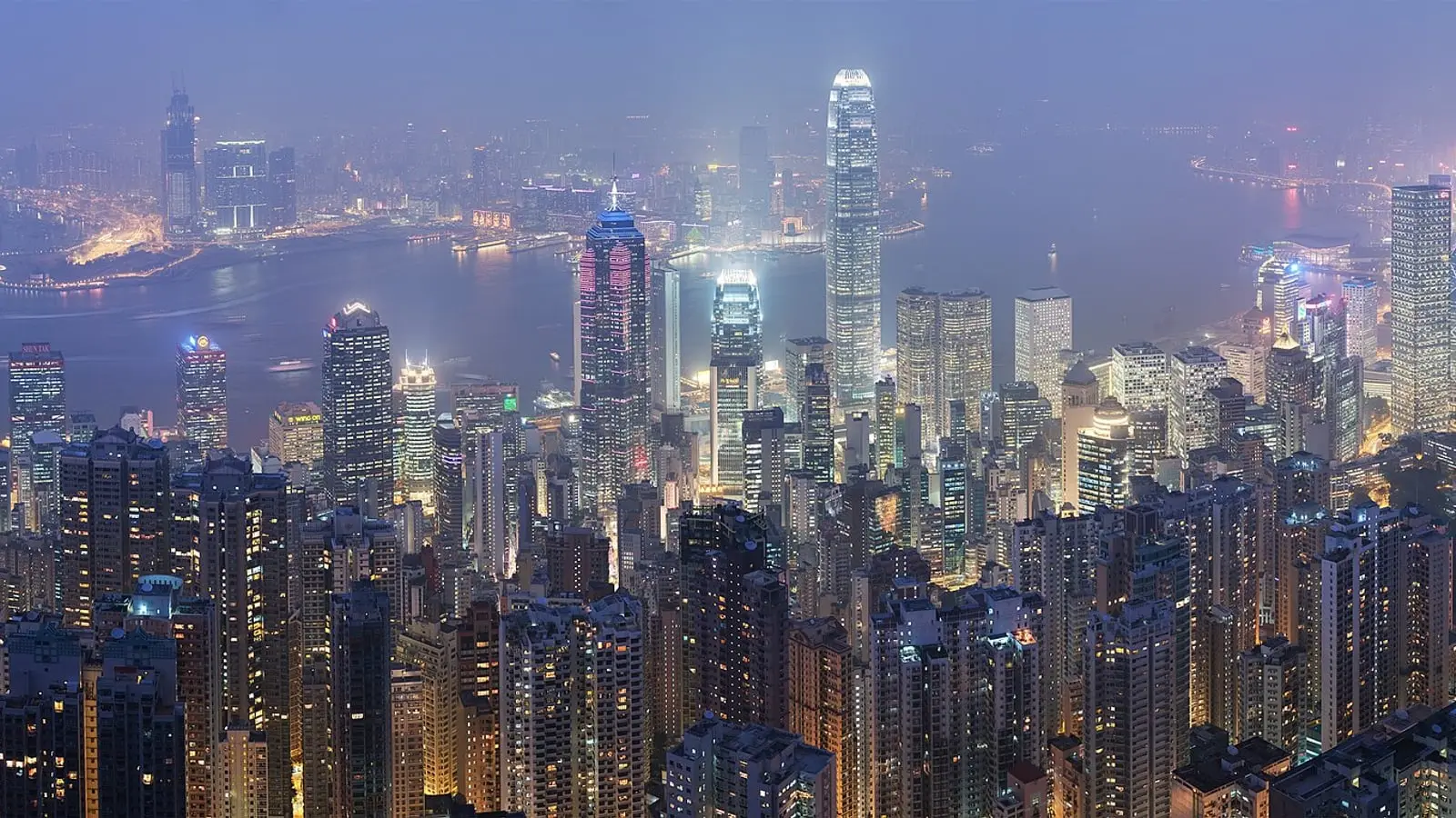 Dazzling evening skyline illumination across Victoria Harbour framed by mountain silhouettes.