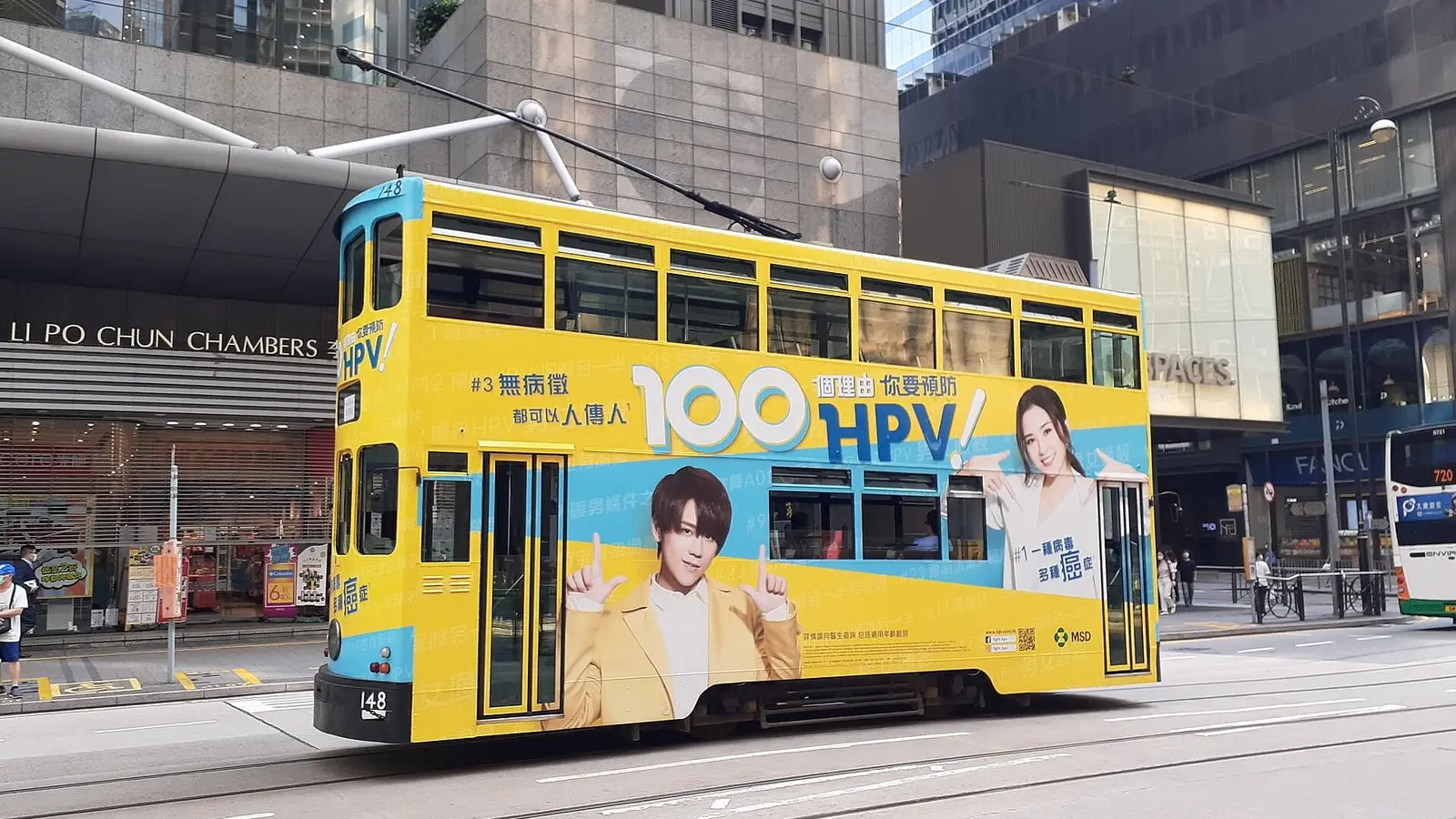 Double-decker tramcars and red urban taxis navigating bustling Des Voeux Road Central.
