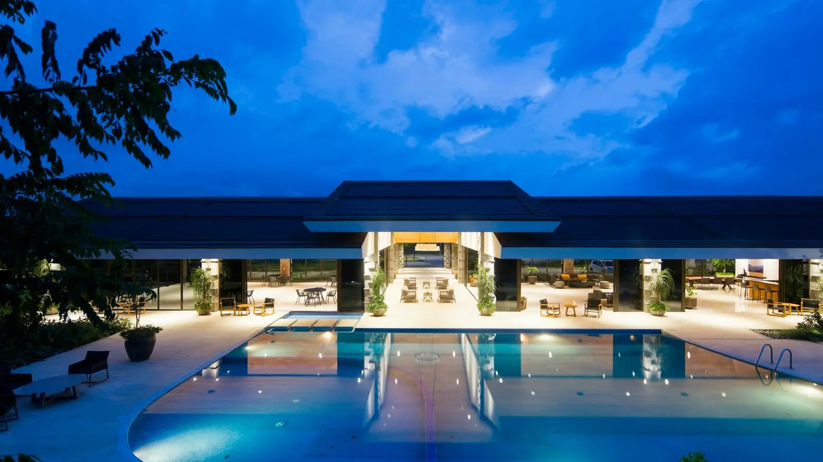Grand exterior facade of an iconic five-star urban hotel illuminated with evening driveway fountains