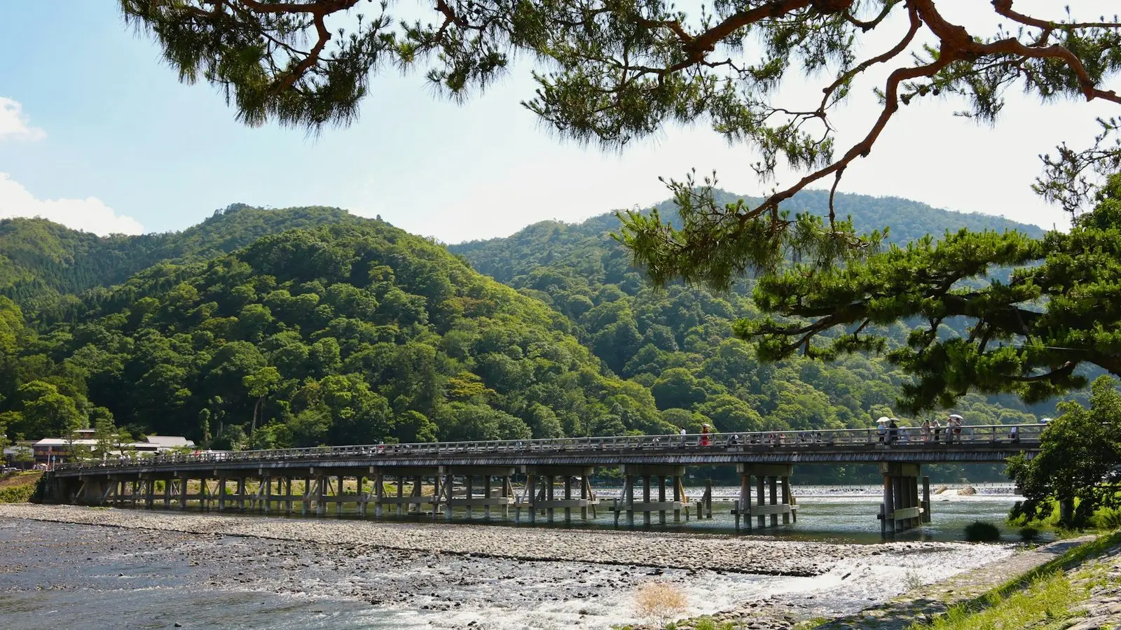 朝日を浴びて大堰川（桂川）を優雅に渡る嵐山の象徴、木造欄干が美しい渡月橋のパノラマ