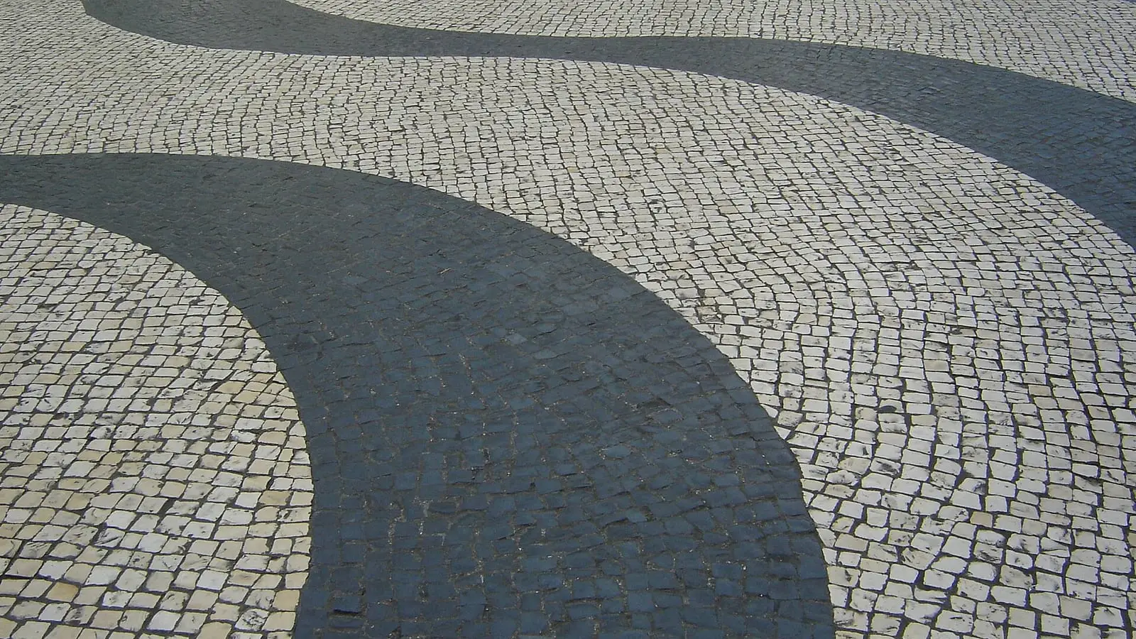 Wave-patterned black-and-white Portuguese calcada mosaic stones lining historic Senado Square in Macau