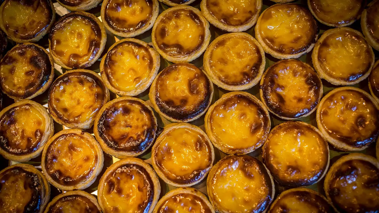 Caramelized, flaky-crusted Macanese Portuguese egg tarts fresh from the bakery oven