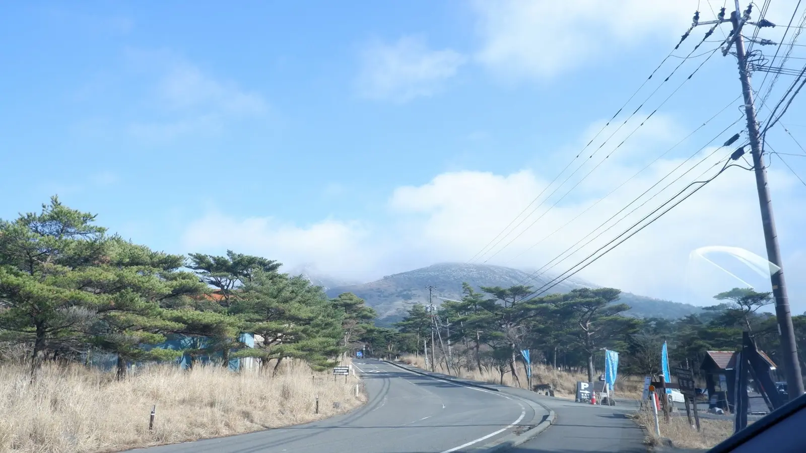 Scenic winding highway through the volcanic plains of Mount Aso in Kyushu under dramatic open skies