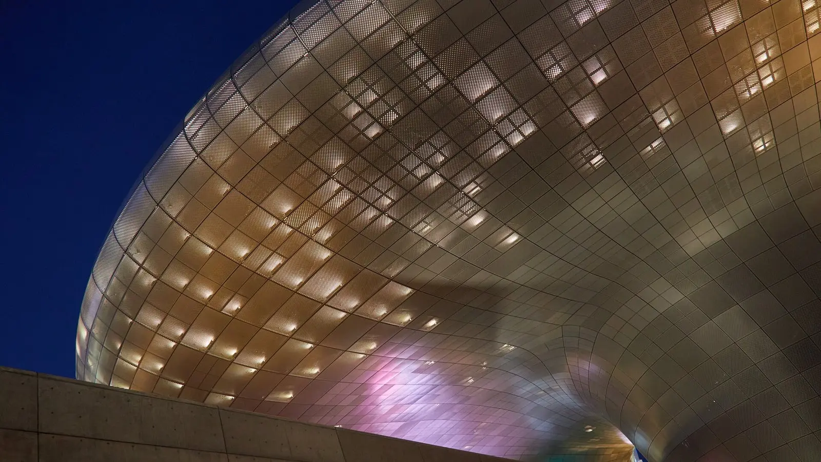 Flowing silver aluminum curves illuminating the night sky at Dongdaemun Design Plaza in central Seoul