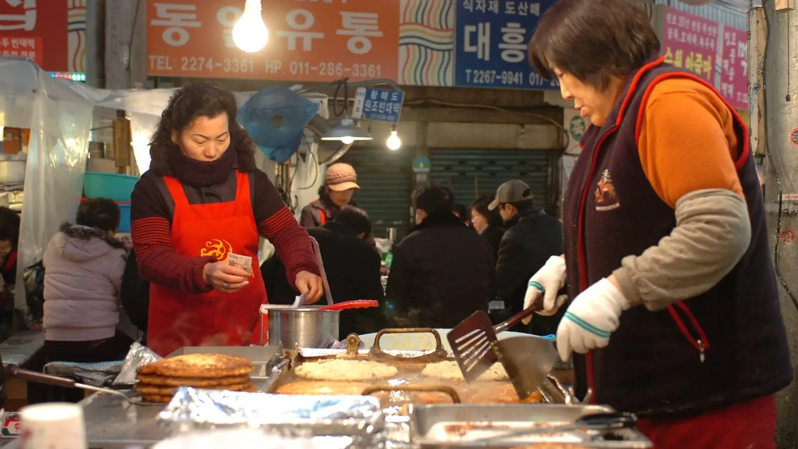 Golden crispy mung-bean pancakes sizzling on cast-iron griddles in the bustling alleys of Gwangjang Market