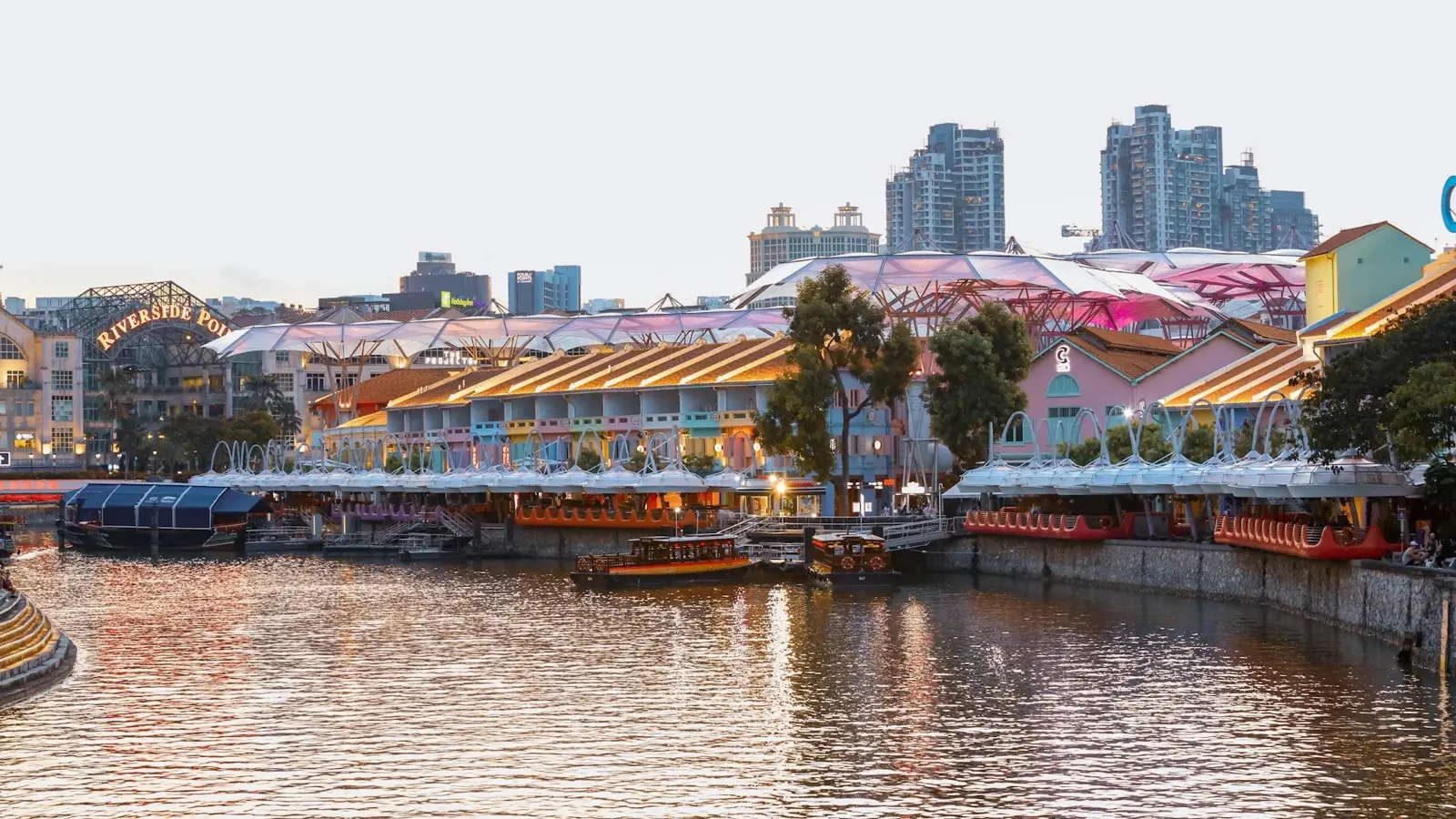 Vibrant riverside nightlife promenade and illuminated alfresco dining terraces along Clarke Quay at dusk